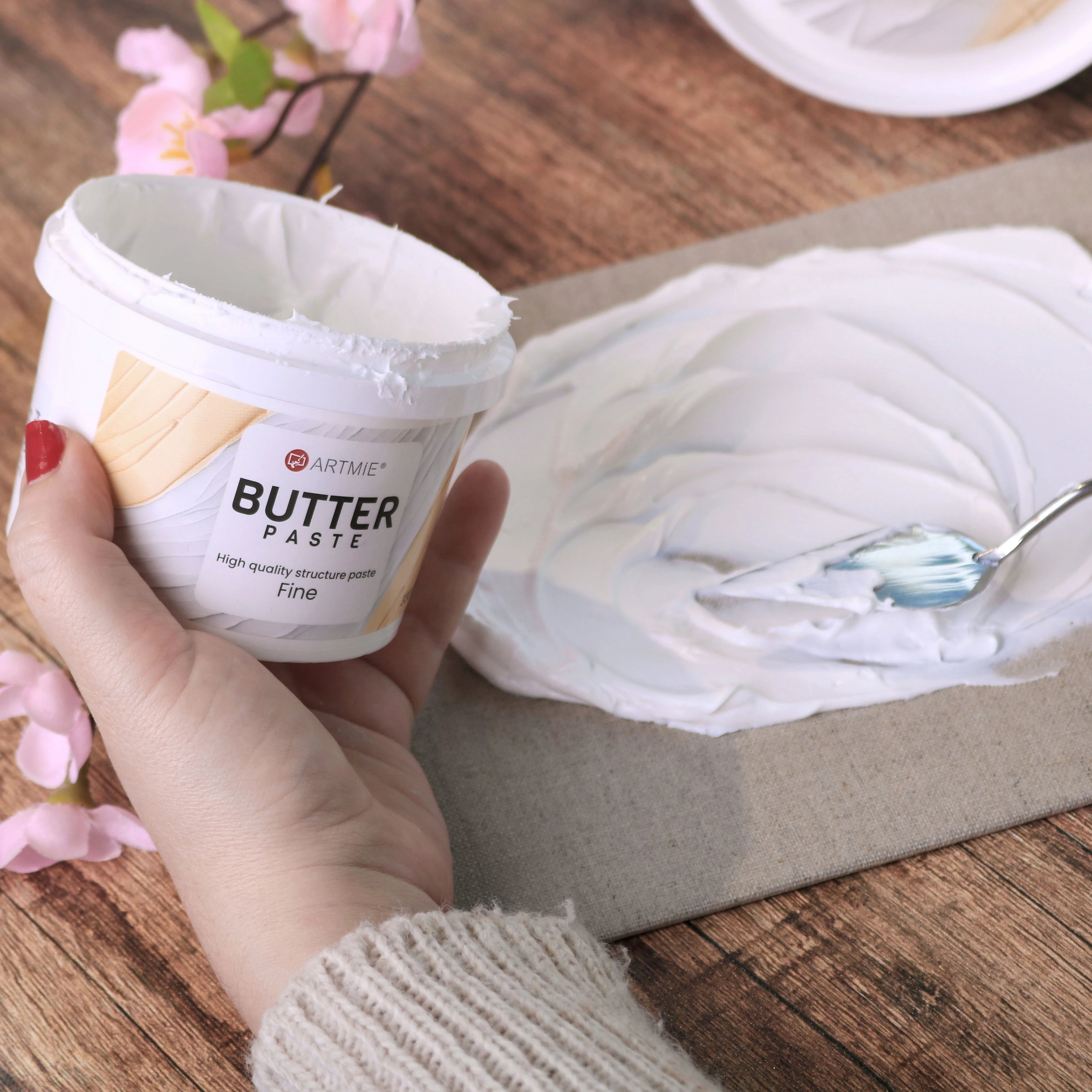 Otevřený kelímek a vrstva pasty ARTMIE Butter Fine nanesená na plátno špachtlí